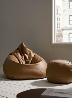 a bean bag chair and ottoman on a white wooden floor in front of a window