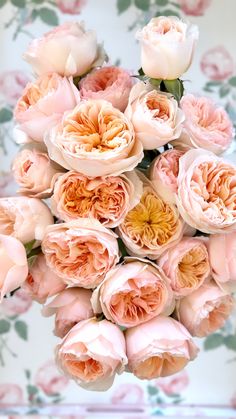 a bouquet of pink roses in front of a floral wallpaper