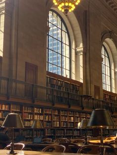 a large library with many bookshelves and lamps on the tables in front of them