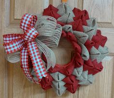 a red and white wreath on the front door with some burlocks around it