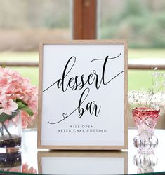 a dessert bar sign sitting on top of a table next to vases and flowers