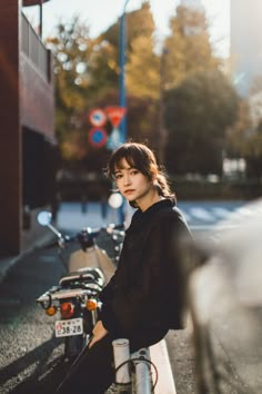 a woman sitting on the side of a road next to a parked motorbike