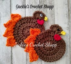 two crocheted turkeys sitting next to each other on a white wooden surface