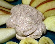 an arrangement of sliced apples and bananas with a dip in the center, on a blue plate