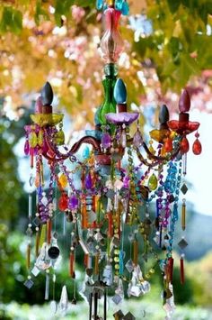 a chandelier with many colorful beads hanging from it's sides in front of a tree