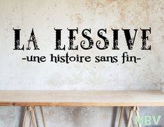 a wooden table sitting in front of a wall that says la lessive une historic sans fin