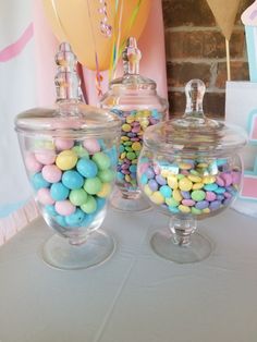 two glass containers filled with candy on top of a table