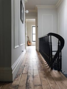 an empty hallway with wooden floors and black railings