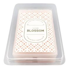 a candle that is sitting in a plastic container on a white surface with the word blossom written