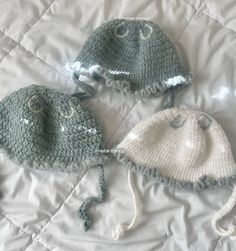 three crocheted hats laying on top of a bed