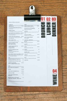 a clipboard with a menu attached to it on a wooden table next to a bottle opener