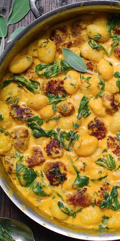 Creamy Pumpkin Gnocchi with Spinach and Sausage in a stainless steel pan.