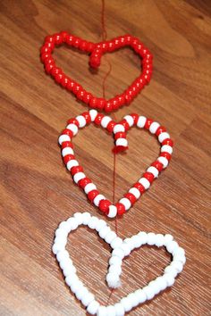 two red and white heart shaped beads on a wooden table with string attached to them