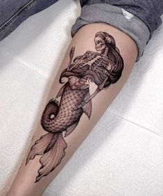 a woman's leg with a skeleton and fish tattoo on it