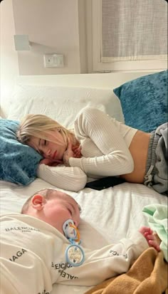 a woman laying on top of a bed next to a baby