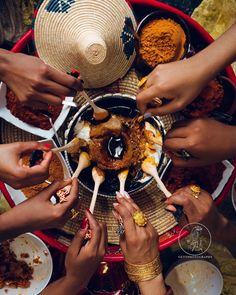 several people holding chopsticks over a bowl full of food with spices on it