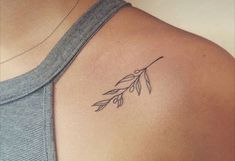 a woman with a tattoo on her shoulder that has an olive branch in the middle