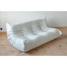 a white futon sofa sitting on top of a hard wood floor next to a wall