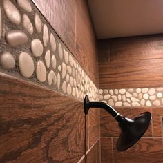 a shower head and hand held faucet in a bathroom with wood tile on the walls