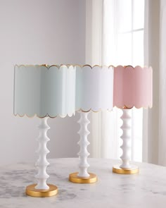 two lamps sitting on top of a table next to each other in front of a window