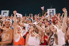 a group of people standing in front of a crowd holding up their hands and smiling