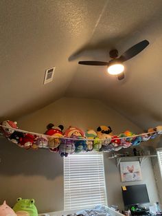 a ceiling fan is hanging from the ceiling above a bed with stuffed animals on it