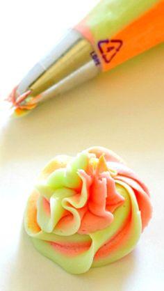 an orange and green cupcake next to a pen