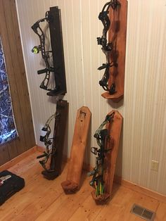 three wooden skis are lined up on the floor in front of a wall with several pairs of skis mounted to it