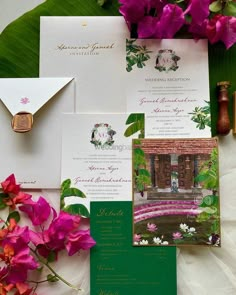 the wedding stationery is laid out with pink flowers and greenery, including orchids