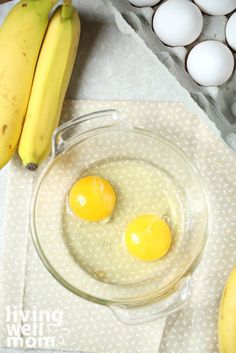 two eggs are in a bowl next to some bananas