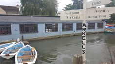 several boats are docked in front of a blue building on the side of a river