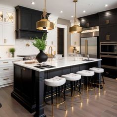 a kitchen with black and white cabinets, gold accents and stools in the center