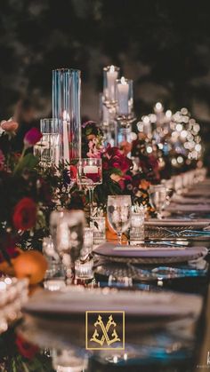 a long table is set with candles, plates and wine glasses for an elegant dinner