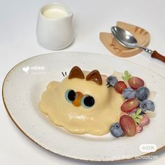 a white plate topped with fruit covered in icing next to a cup of milk