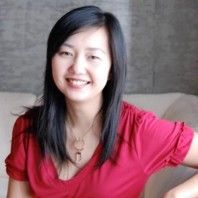 a woman in a red shirt is sitting on a couch and smiling at the camera