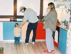 a man and woman standing in a kitchen with a toddler