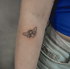 a small black and white bee tattoo on the arm