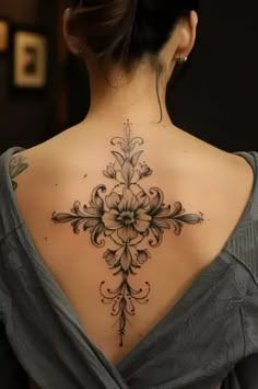 the back of a woman's neck with an intricate tattoo design on her left shoulder