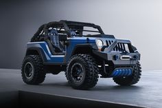 a blue jeep parked on top of a cement floor in front of a gray wall