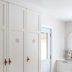 a bedroom with white cupboards and a mirror