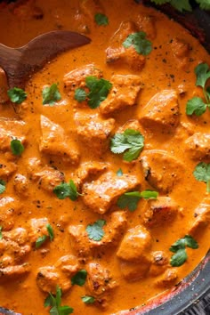 a skillet filled with chicken curry and garnished with cilantro