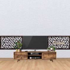 a flat screen tv sitting on top of a wooden entertainment center next to a plant