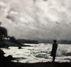 a man standing on top of a beach next to the ocean under a cloudy sky