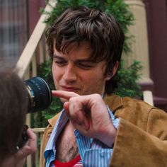 a man holding a camera up to his face and pointing at something in front of him