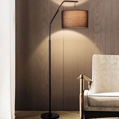 a living room with a chair and lamp on the floor next to a wooden wall