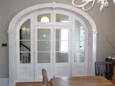 a dining room table and chairs in front of an arched doorway with glass paneling