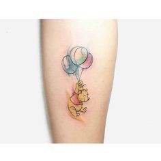 winnie the pooh tattoo with balloons on her leg and an elephant holding onto it