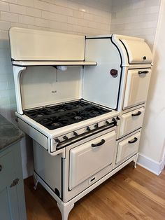 an old fashioned white stove and oven in a kitchen with wood floors, cabinets and counter tops