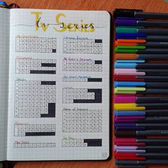 an open notebook with several different colored pencils next to it