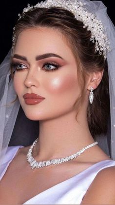 a woman wearing a bridal veil and tiara with pearls on the headband